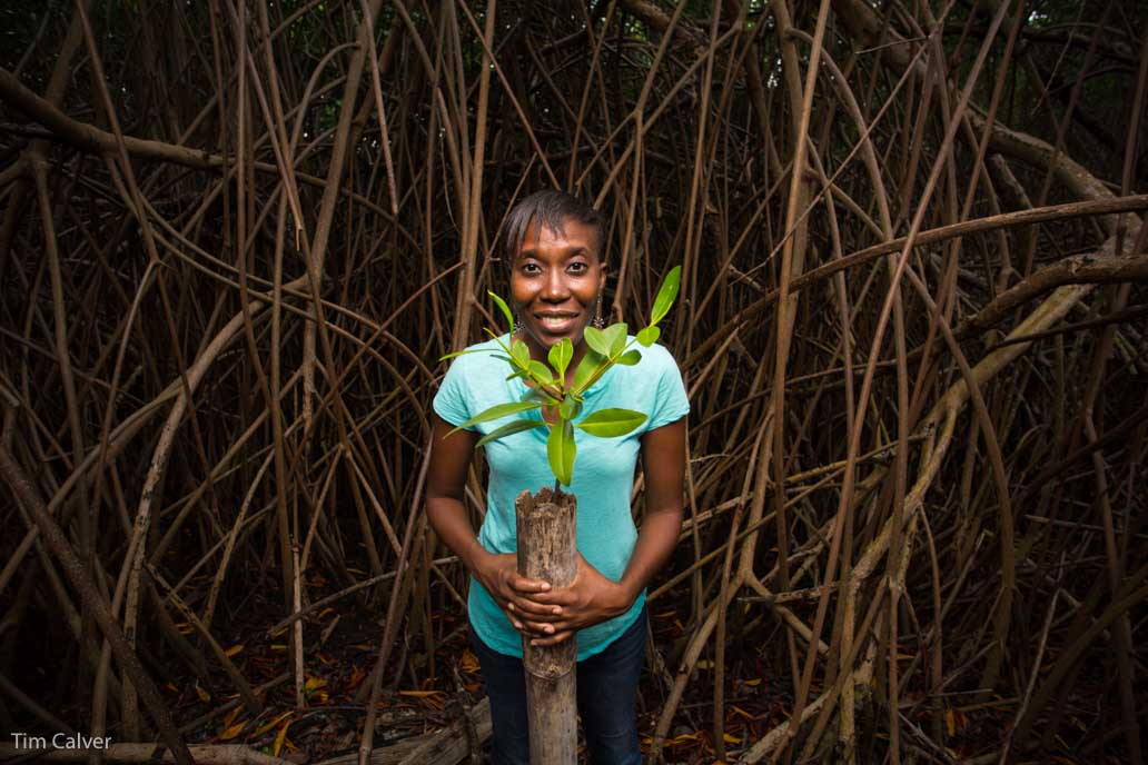 Person standing smiling in front of forest.