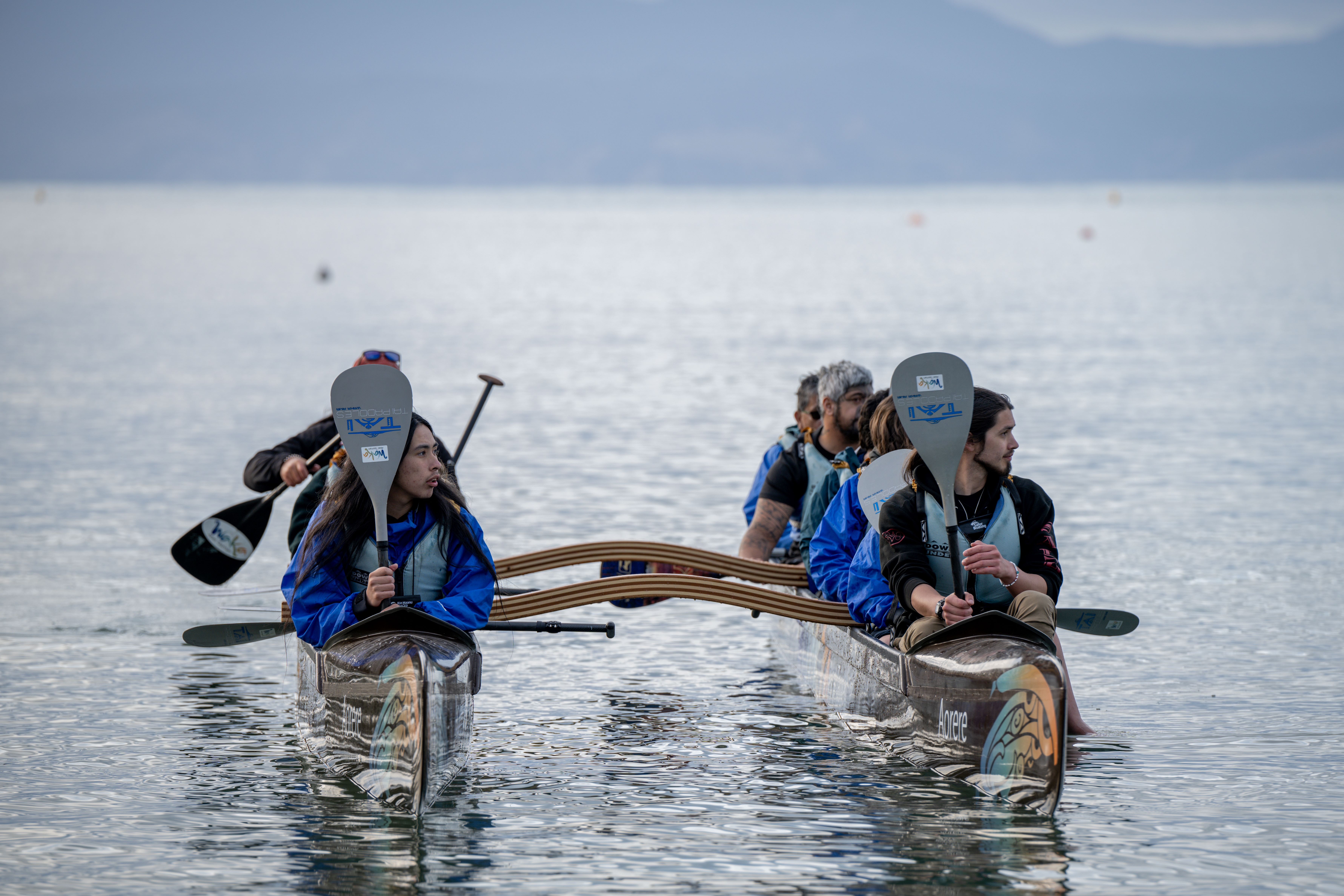 People paddling a double canoe. 