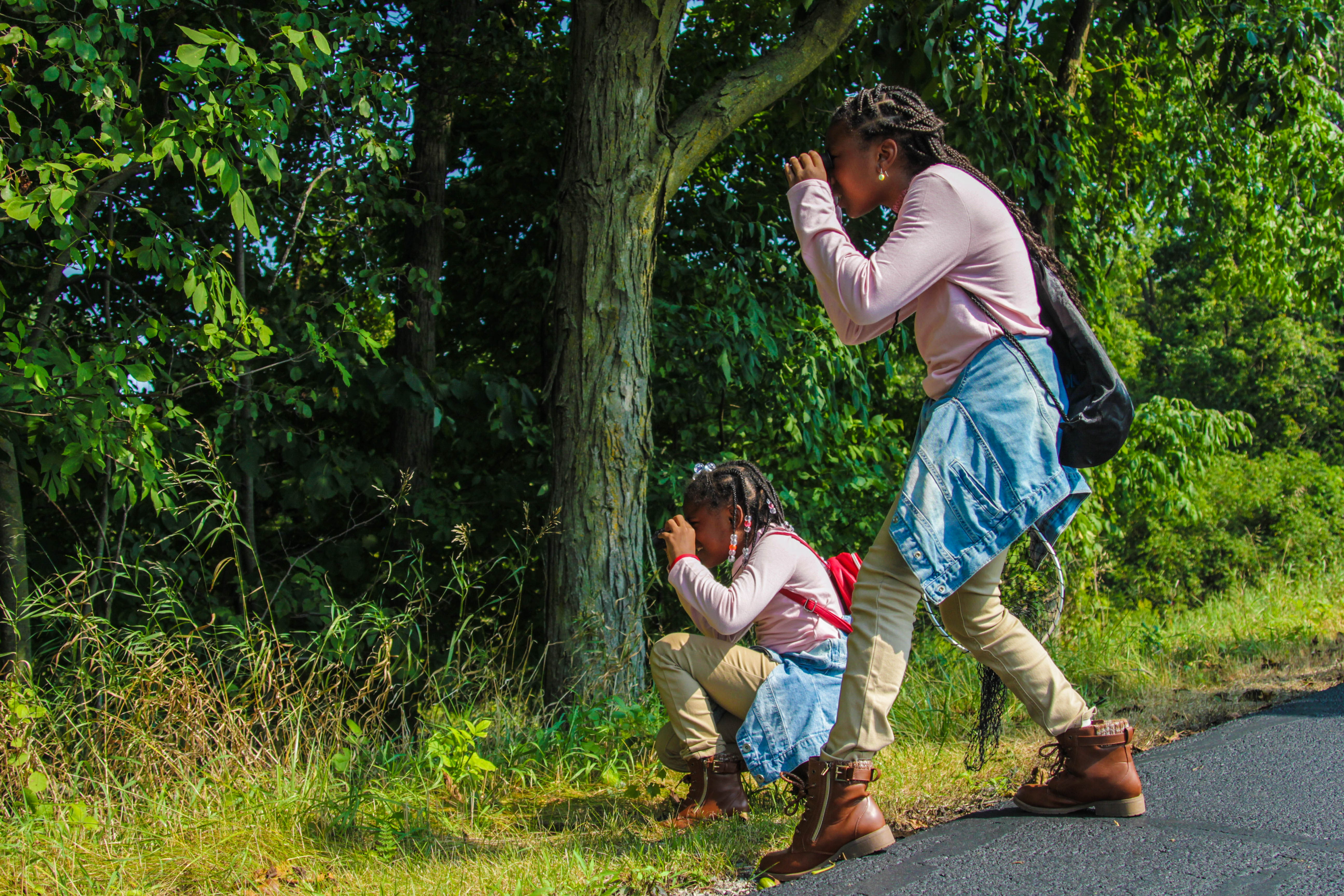 Two children in nature with binoculars.